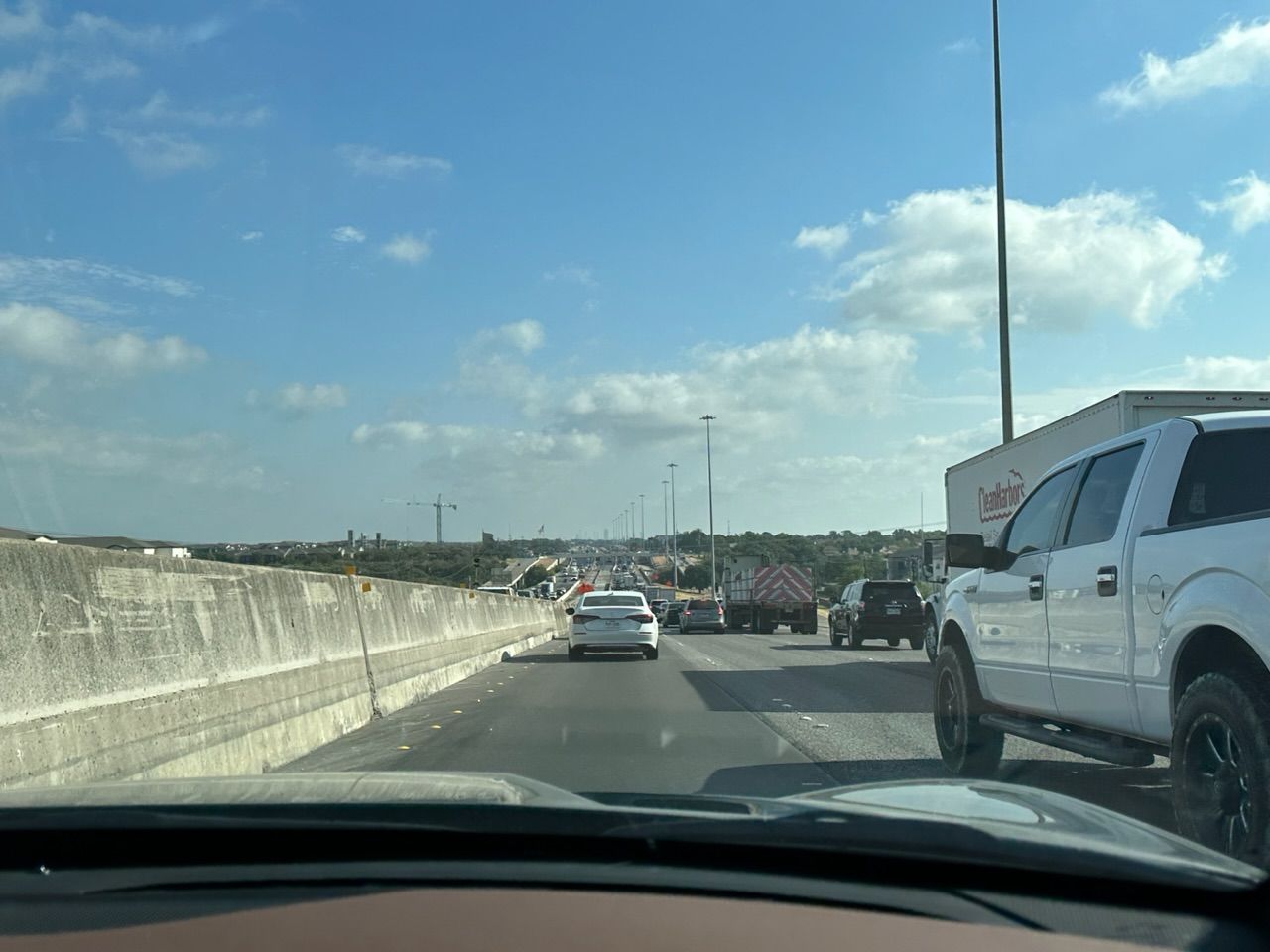 Stop and go traffic on a busy highway, with some construction work visible.